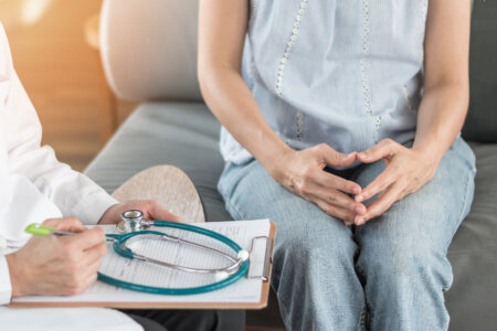 Woman sitting at doctor's office with hands together.