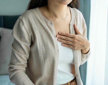 Female holding her chest, feeling discomfort from struggling to breathe.