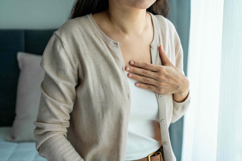 Female holding her chest, feeling discomfort from struggling to breathe.
